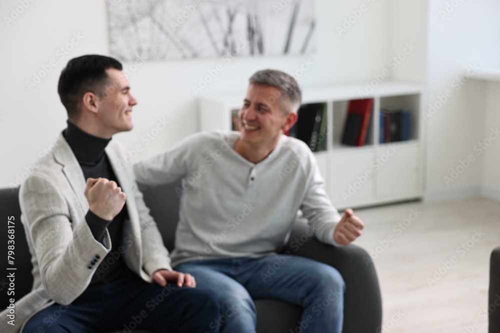 Blurred view of happy men talking while sitting on sofa at home Blurred view of happy men talking while sitting on sofa at home