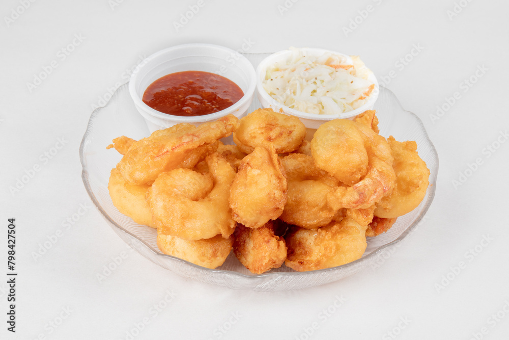 A plate of deep fried breaded shrimp with coctail sauce and coleslaw on a white background A plate of deep fried breaded shrimp with coctail sauce and coleslaw on a white background