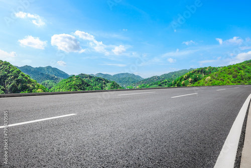 Asphalt highway road and green mountains with sky clouds nature landscape on sunny day © ABCDstock
