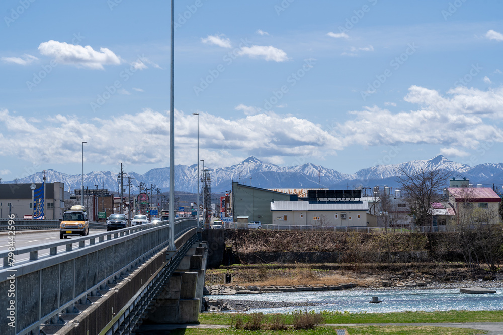Obraz premium 北海道の風景 歴舟川に架かる橋と遠くに連なる日高山脈