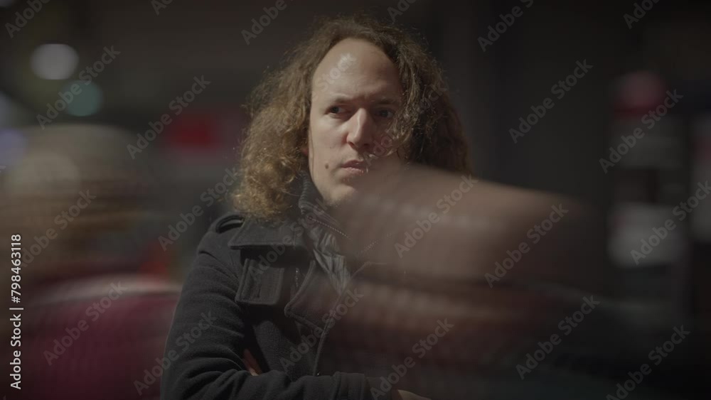 A man with long hair stands in the dark, staring at the camera with lens flare A man with long hair stands in the dark, staring at the camera with lens flare