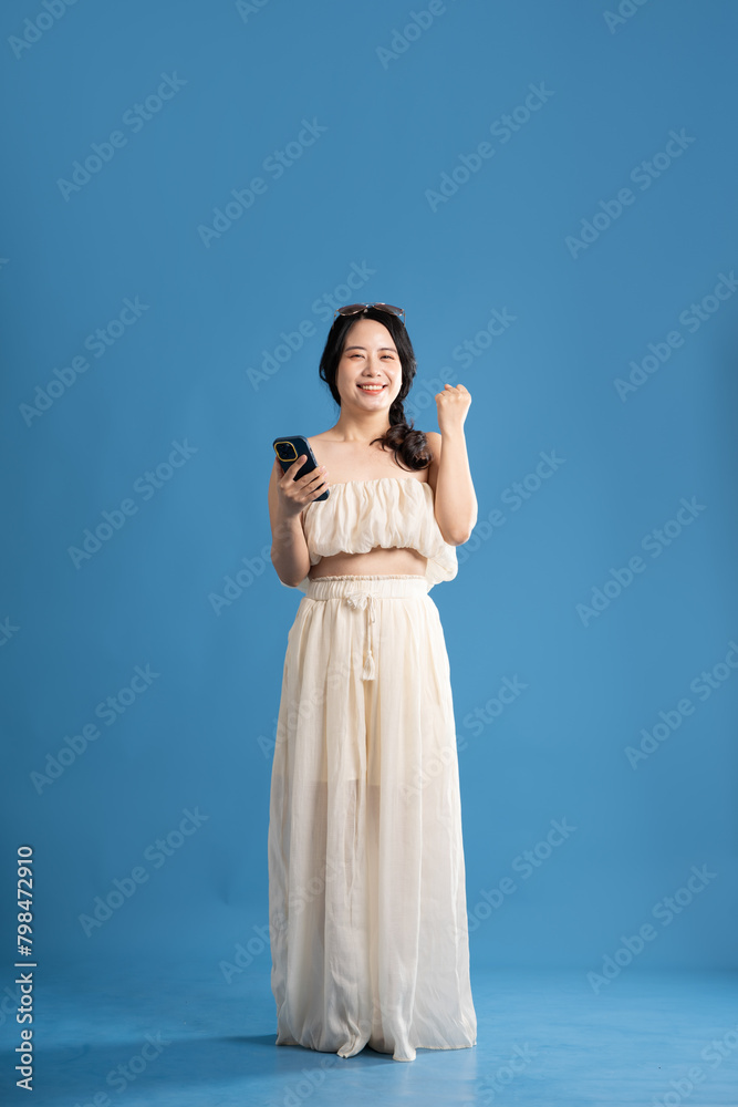 Portrait of asian girl posing on blue background, traveling in summer