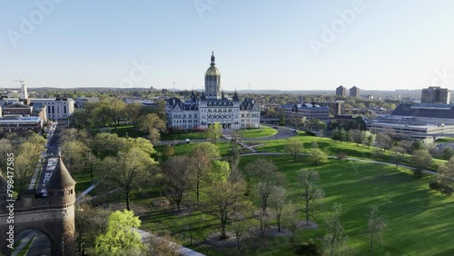Wide establishing drone shot of the Connecticut State Capitol building on a sunny spring day with aerial view over Bushnell Park in Hartford, CT photo