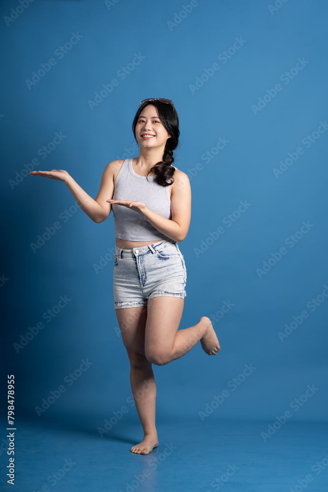 Naklejka premium Portrait of asian girl posing on blue background, traveling in summer