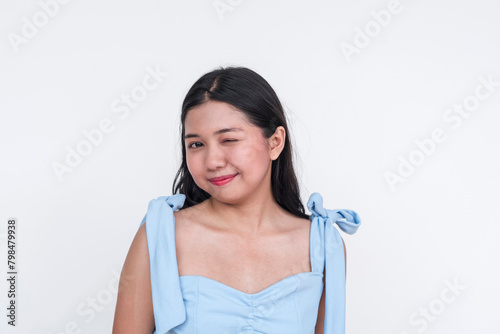 Charming young Asian woman winking in a powder blue dress, isolated on white