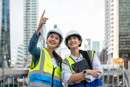 Two Asian confident engineer woman working together with a cityscape in the background