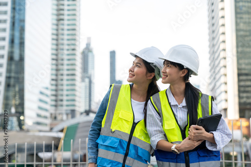 Two Asian confident engineer woman working together with a cityscape in the background