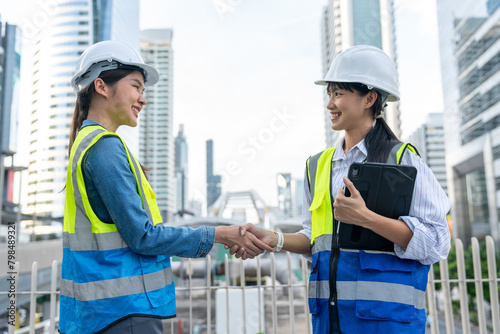 Asian Technician, Engineer doing handshake together with a cityscape in the background