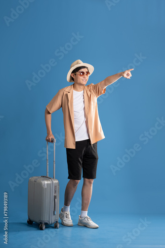 Portrait of Asian man posing on blue background, traveling in summer