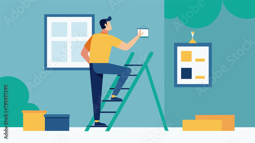 A man sitting on a ladder hammering in picture frames on a freshly painted feature wall in his bedroom..