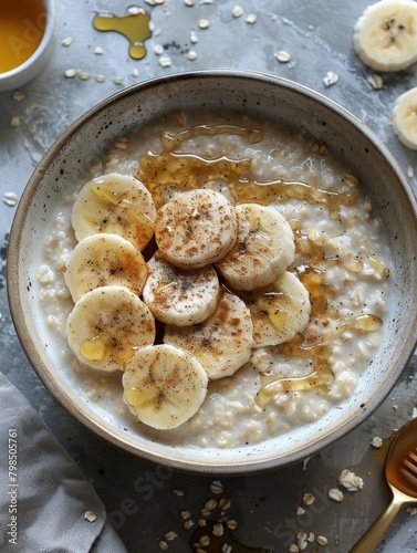A shot of a bowl of oatmeal topped with sliced banana and honey.