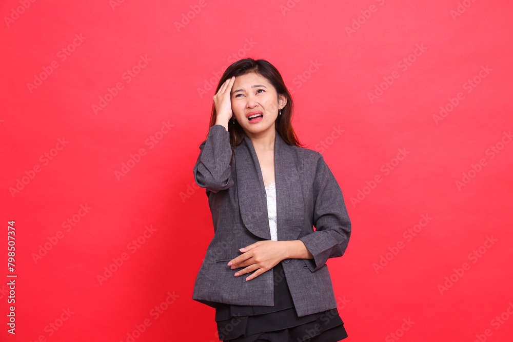 expression of asian office girl holding head dizziness and candid headache wearing gray jacket and red background skirt. for health, business and advertising concepts