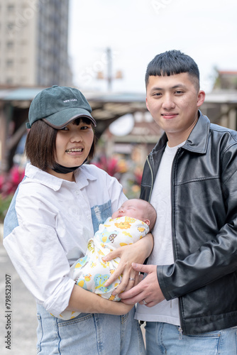 A mother and father in their 20s living in Yilan, Taiwan, are in a car holding a one-month-old Taiwanese baby.
台湾宜蘭に住む２０代の母親と父親が生後一ヶ月の台湾人の赤ちゃんを抱っこして宜蘭県羅東車站の前で立っている