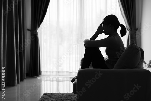 Depressed woman, Silhouette of teenager girl with depression sitting alone in the dark room. Black and white photo.