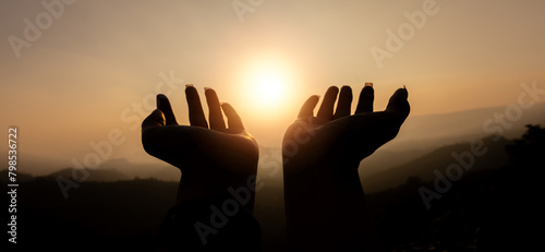 Silhouette of Person women hand  demonstrating their religious faith. women hand in prayer, expressing his religious faith in God through worship of Jesus Christ.turned to God in prayer.