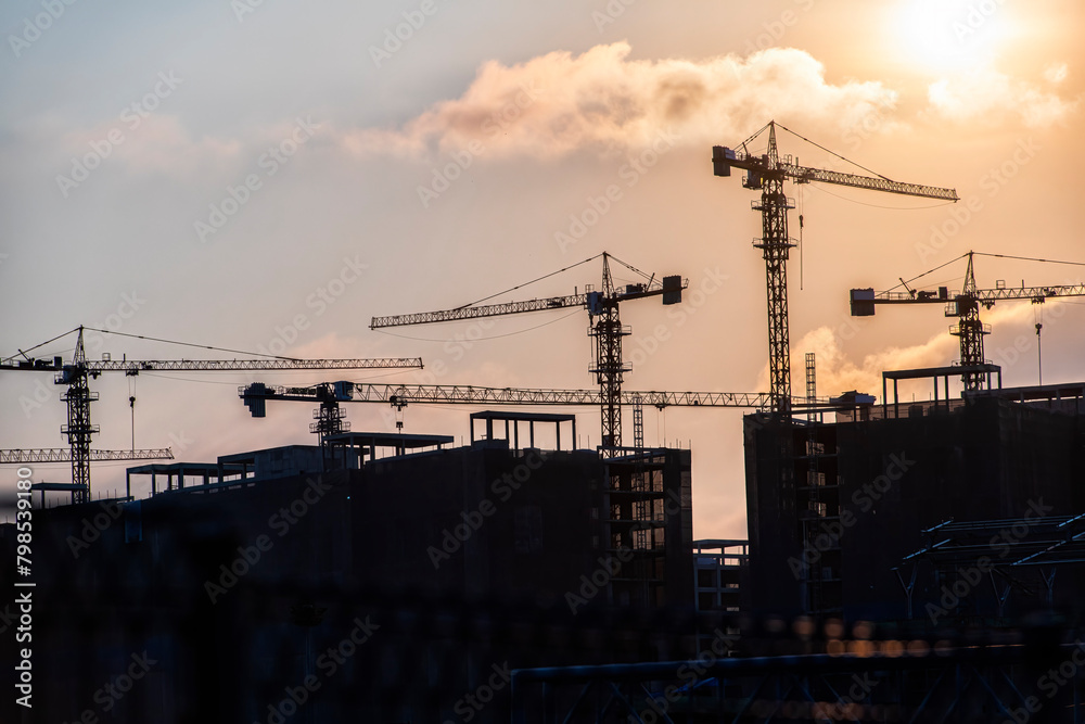 silhouette of a building. silhouette of a crane. photo of site construction while sunset.