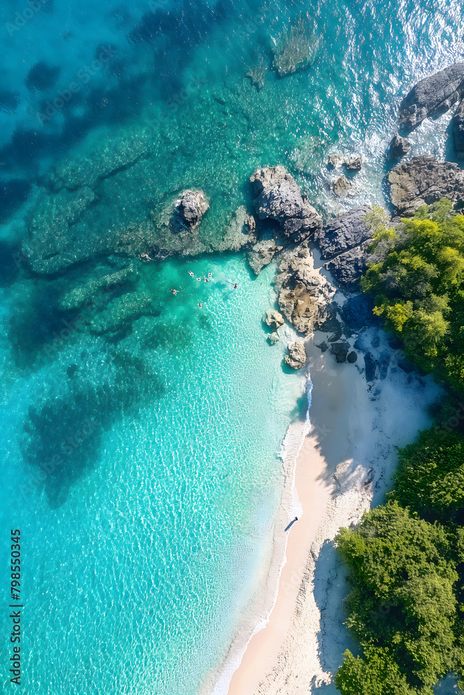 An aerial perspective of a hidden beach with turquoise water surrounded by rocky outcrops and lush trees.