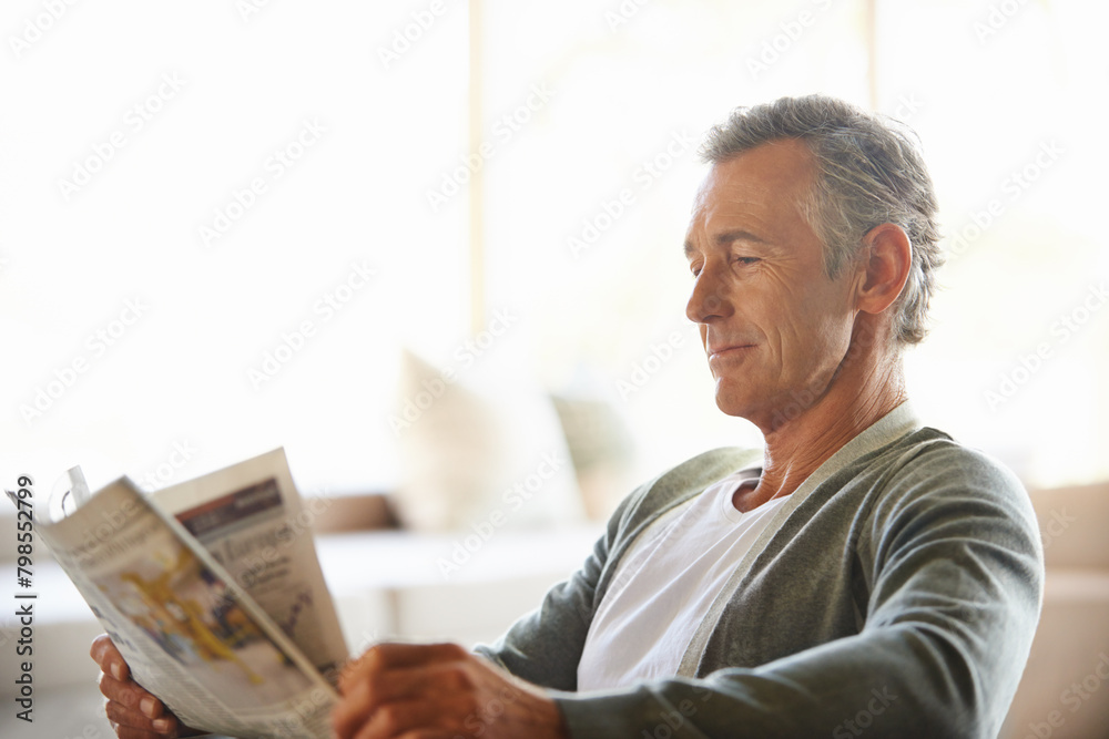 Fototapeta premium Mature, man and newspaper for reading in home, relax and information or articles in morning with coffee. News, breakfast table and rest and calm for entertainment pages, current events in apartment