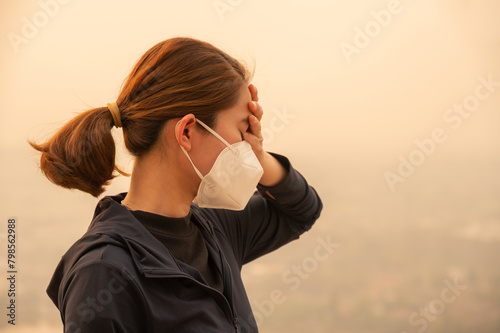 Asian woman having headache becaused of by Bad air pollution (PM2.5). PM2.5 levels meaning the air quality posed a health hazard.