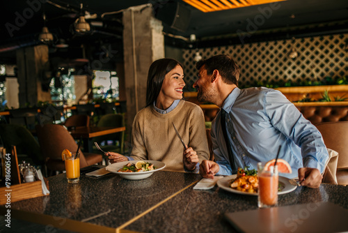 Cheerful couple sitting in a restaurant  having lunch and chatting