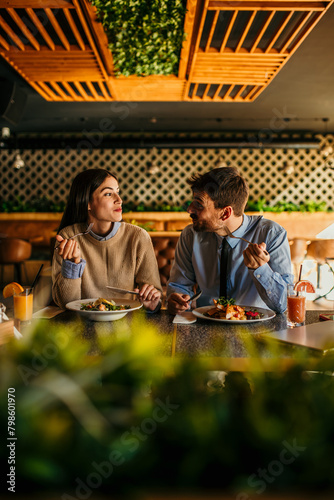 Happy young woman eating lunch with her boyfriend in a restaurant