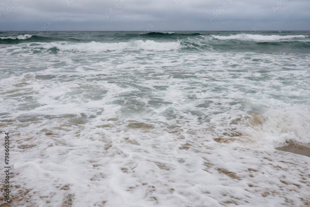 View of the surf on the snowing sand beach