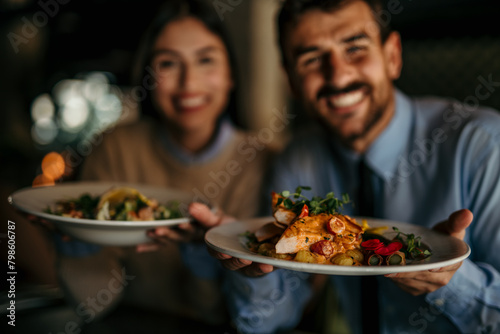 Portrait of a smiling couple holding a dishes in the restaurant and smiling