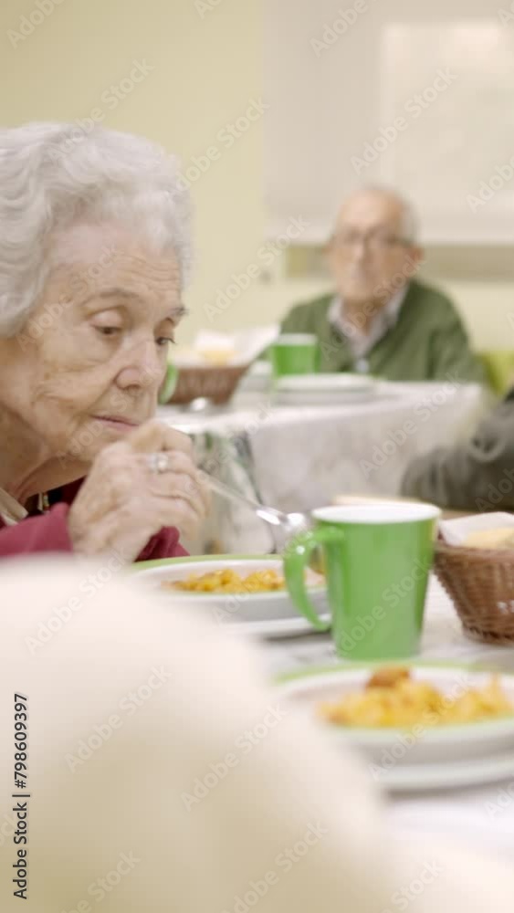 Senior woman eating and talking sitting in geriatric's dinning room Senior woman eating and talking sitting in geriatric's dinning room