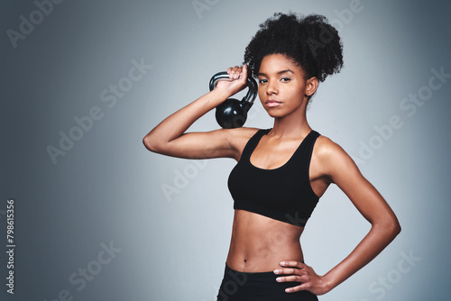 Portrait, black woman and workout with kettle bell in studio on grey background to exercise for health or fitness. Female person, confident and weights for gym or training, wellbeing and wellness