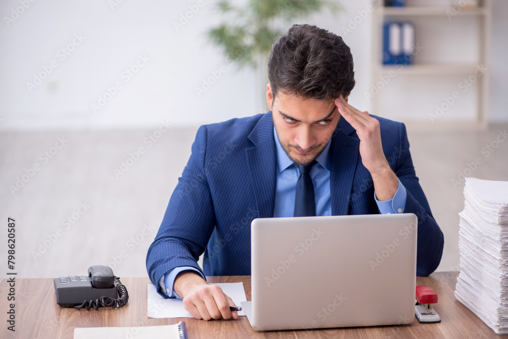 Young male employee and too much work in the office Young male employee and too much work in the office