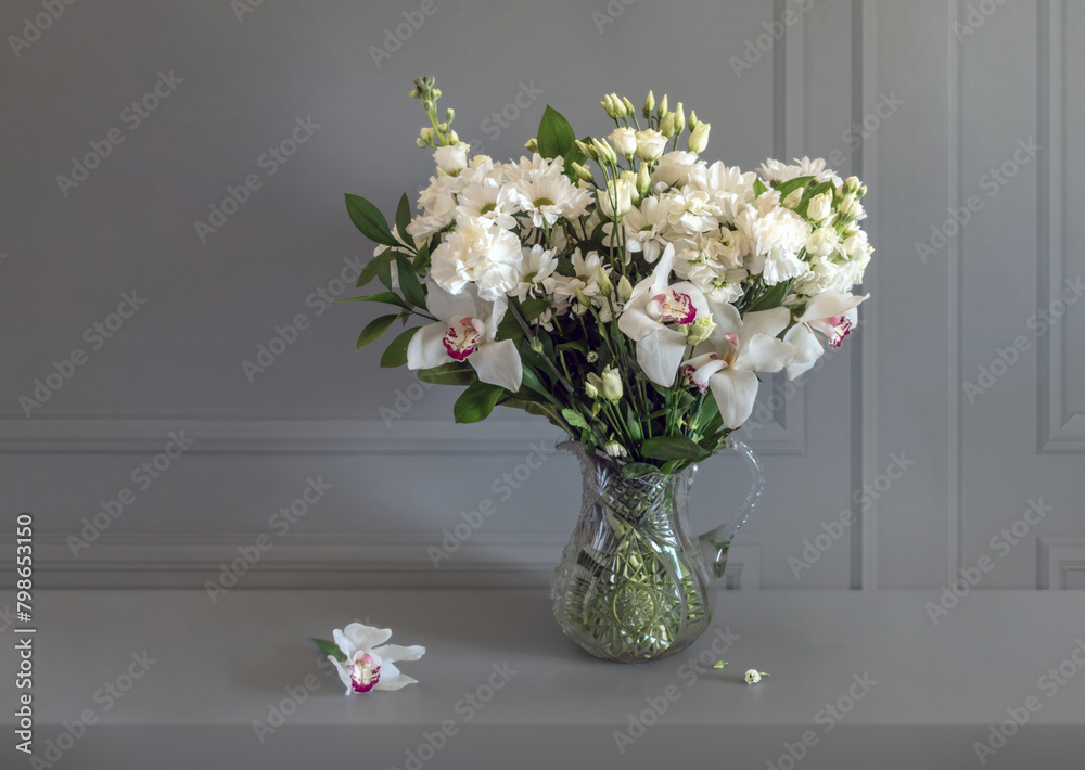 A bouquet of white flowers in a crystal jug.
