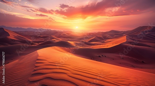  Sun sets, sand dunes in foreground, mountains with clouds in distance
