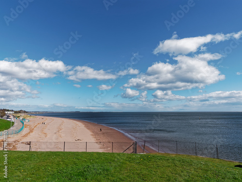 Broughty Ferry Beach on the Tay Estuary on a fine Spring day in April, with Walkers enjoying the sunshine as they stroll on the Beach.
