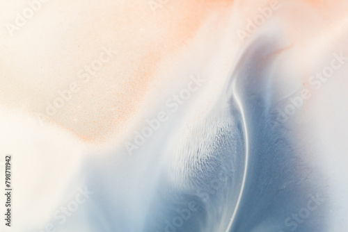 Liquid paint abstract background. Blue and white acrylic paints with shimmering golden glitter 