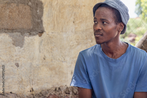 village african man in the yard, profile view, casual clothing with blue shirt
