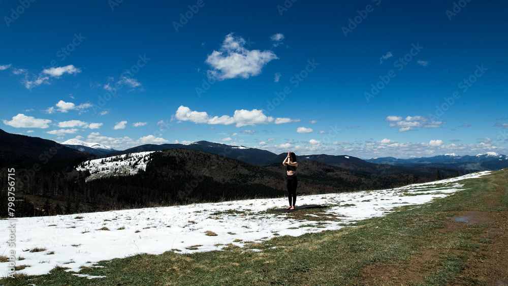 A woman does yoga and meditates high in the snowy mountains on a sunny day. The concept of yoga and meditation. Concern for mental health A woman does yoga and meditates high in the snowy mountains on a sunny day. The concept of yoga and meditation. Concern for mental health