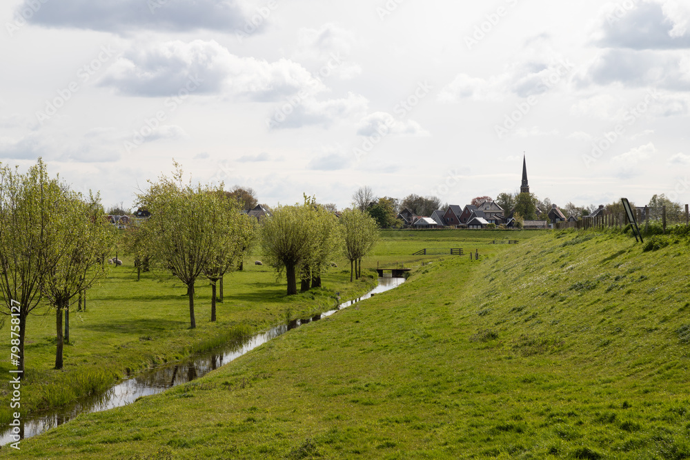 Pasture with sheep and in the background the church tower of the rural village of Ilpendam in North Holland. Pasture with sheep and in the background the church tower of the rural village of Ilpendam in North Holland.