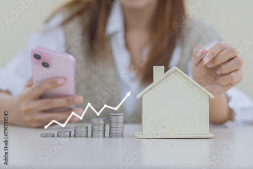 woman puts coins into a wooden house piggy bank. Placing coins in a row from low to high is comparable to saving money to grow more, money-saving concept photo