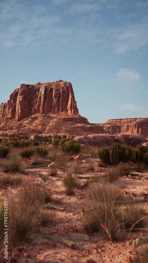 A dry desert with sparse vegetation stretches towards a towering mountain in the distance under a clear sky. A dry desert with sparse vegetation stretches towards a towering mountain in the distance under a clear sky.
