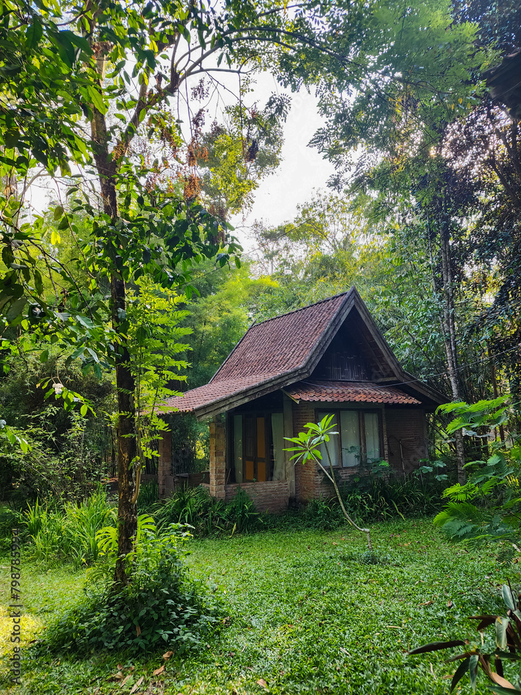 Small house with red brick walls and a red tile roof in a fresh green garden