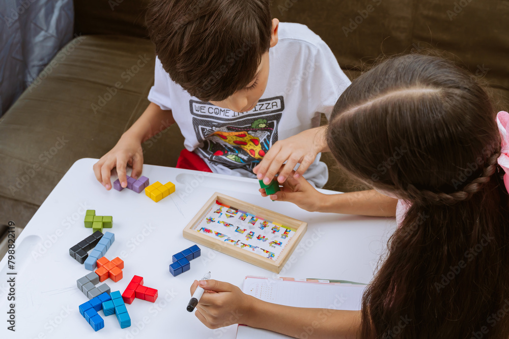 International Children Day. Beautiful Latino children playing with blocks on a white table. Playful, fun and thinking games. Happy children at home. International Children Day. Beautiful Latino children playing with blocks on a white table. Playful, fun and thinking games. Happy children at home.