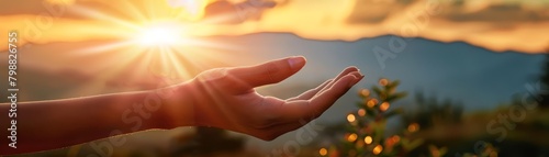 A photo of a hand reaching out towards the sun during the golden hour.