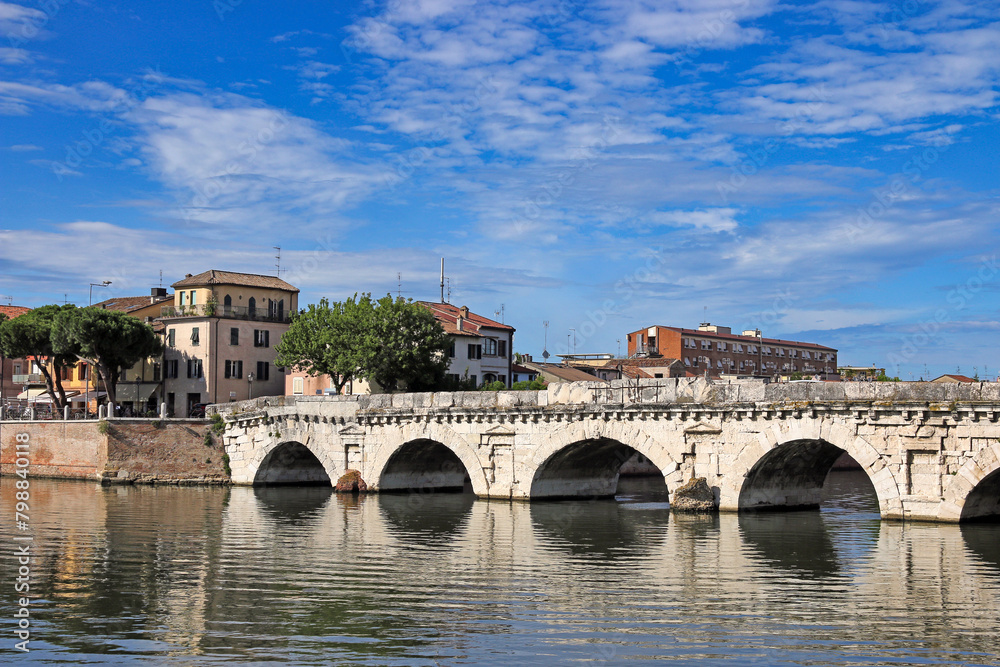 Old stone Tiberius bridge and buildings in Rimini Italy