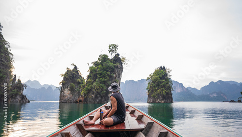 man sitting on the boat and looking to mountains at Khao Sok, Cheow Lan, Surat Thani Province, Thailand.Tourism beautiful destinations Asia holiday vacation trip..