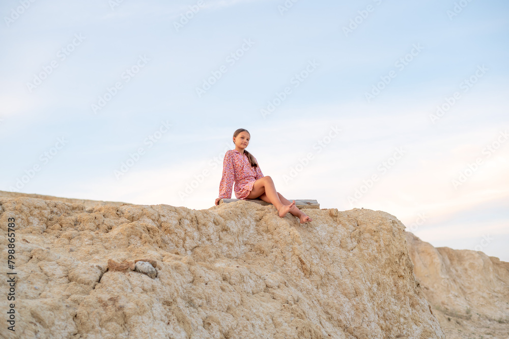 Teenager girl resting in nature, portrait girl sitting on the edge of a mountain.