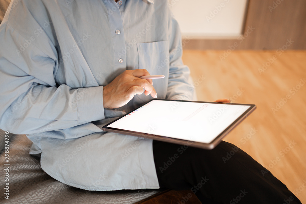 A girl is sitting on the sofa with a tablet in her hand. In the second, she is holding a stylus. A woman works with a tablet.
