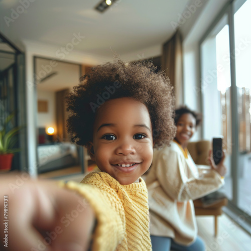 Joyful laughing african american son accidentally takes selfie while spending time at home with mom