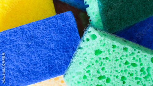 Colorful Cleaning Aids. A stack of blue, green, and yellow sponges. Uses for Cleaning product catalogs, household guides.