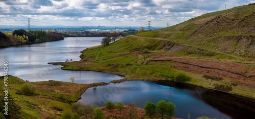  Panoramic aerial view of greenbooth reservoir in Naden valley, Greater Manchester showing the city of Manchester skyline on the distance.
