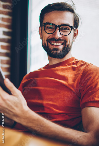 Photos Half length portrait of positive bearded young man in eyeglasses for vision corr